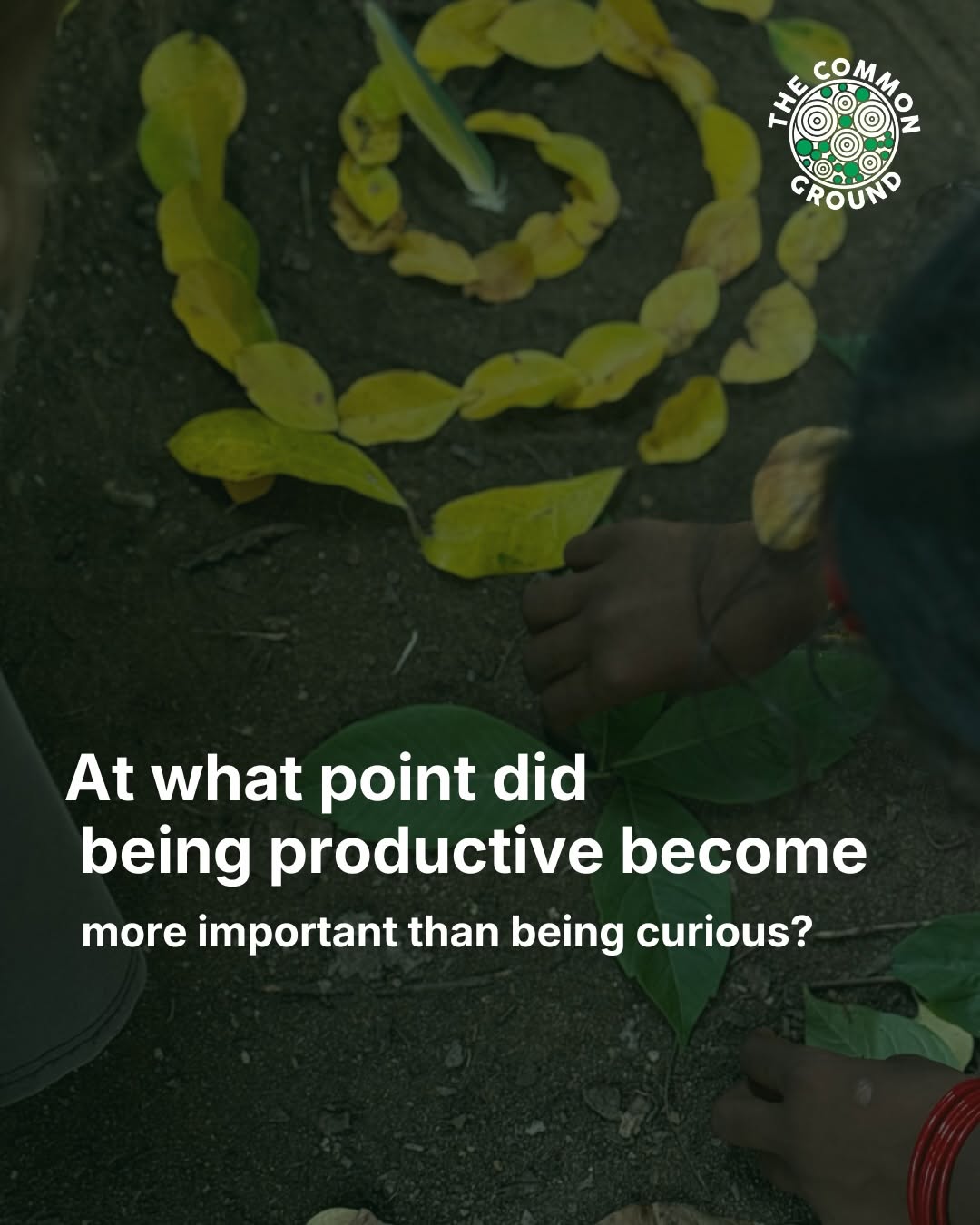 Hands arranging yellow-green leaves into a spiral on dark soil. One wrist has red bangles.
